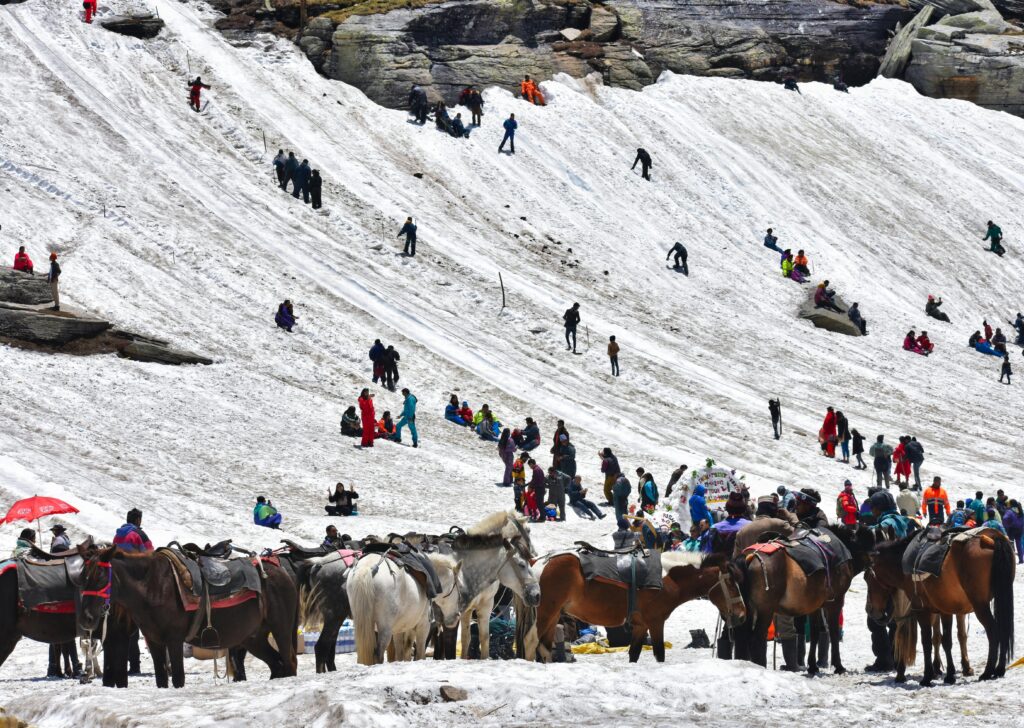 Crowd engaging in winter activities in Kedarnath's snowy landscape.